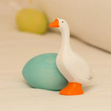 Bumbu handcrafted wooden white goose figure standing next to to a blue egg decorative figure