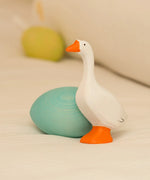Bumbu handcrafted wooden white goose figure standing next to to a blue egg decorative figure