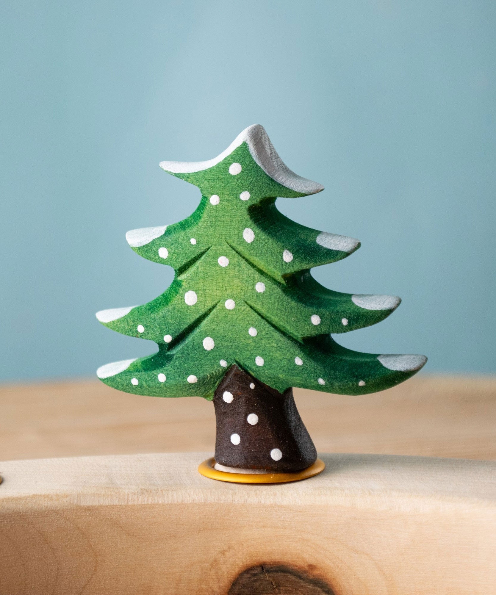 Bumbu Festive Tree Celebration decorative Figure to fit on a Grimm's celebration ring. The figure is a green fir tree decorated with snow.  These festive figures are perfect for your Christmas celebration ring set up. These expertly hand crafted items are part of a large range of wooden toys available here at Babipur. 