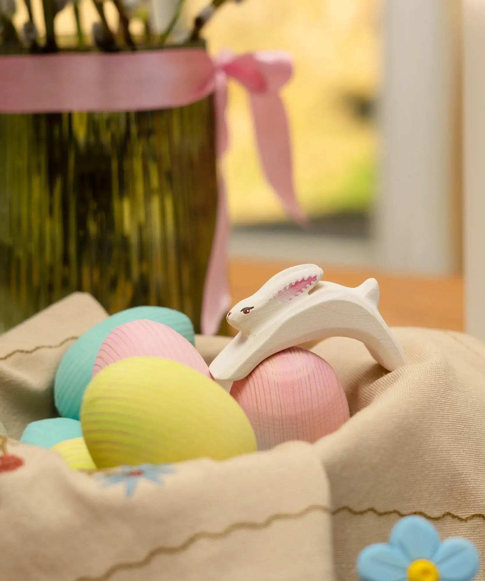 Bumbu handcrafted white rabbit figure standing on wooden eggs resting in a basket
