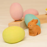 Bumbu handcrafted brown rabbit figure standing next to a yellow, blue and pink wooden decorative figures