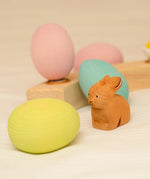 Bumbu handcrafted brown rabbit figure standing next to a yellow, blue and pink wooden decorative figures