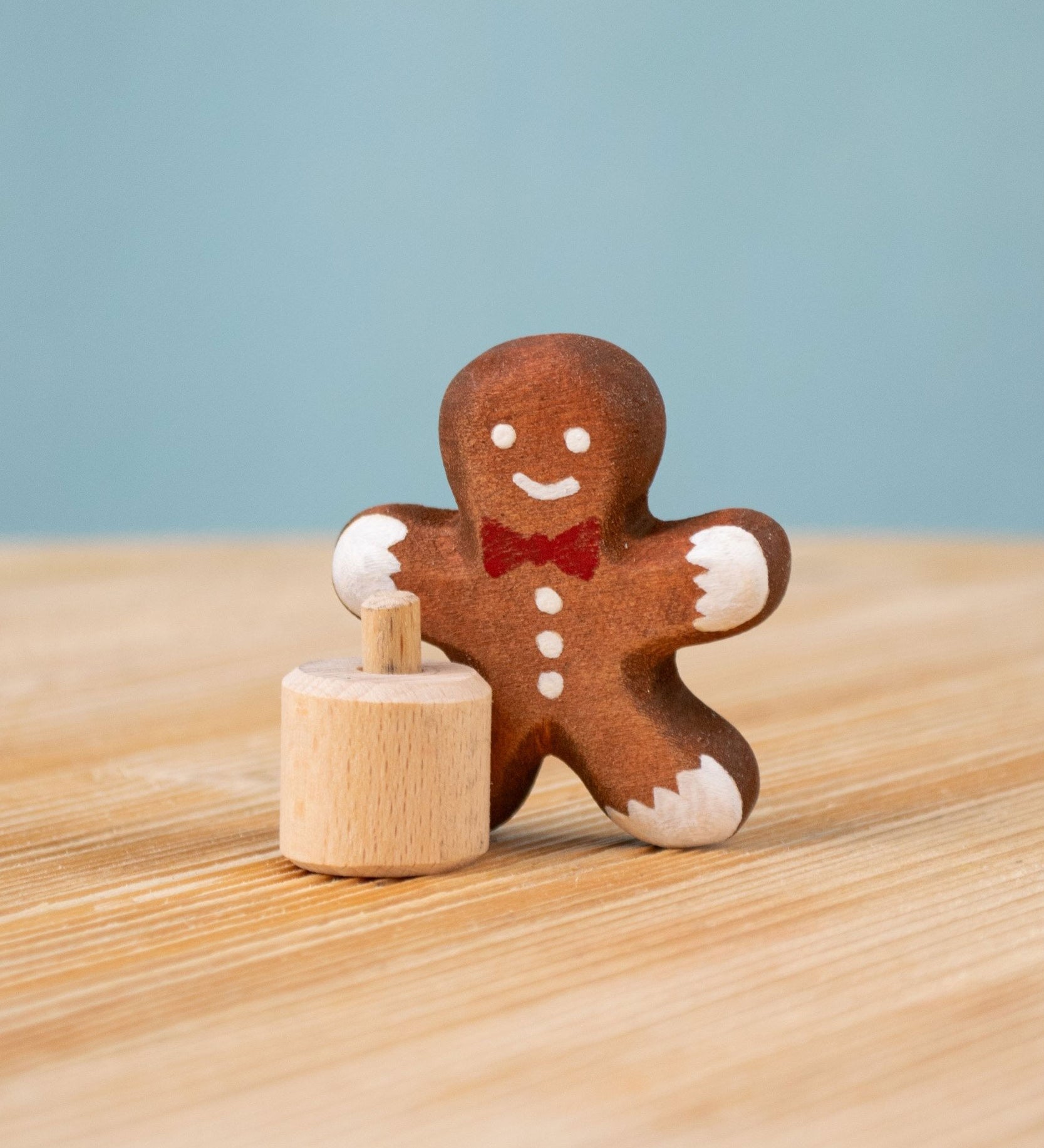 Bumbu Festive Gingerbread man Celebration decorative Figure to fit on a Grimm's celebration ring. The gingerbread man is shown separated from the little wooden base it comes with. These festive figures are perfect for your Christmas celebration ring set up. These expertly hand crafted items are part of a large range of wooden toys available here at Babipur. 