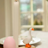 A handcrafted wooden white goose Bumbu decorative figure on a celebration ring next to a candle