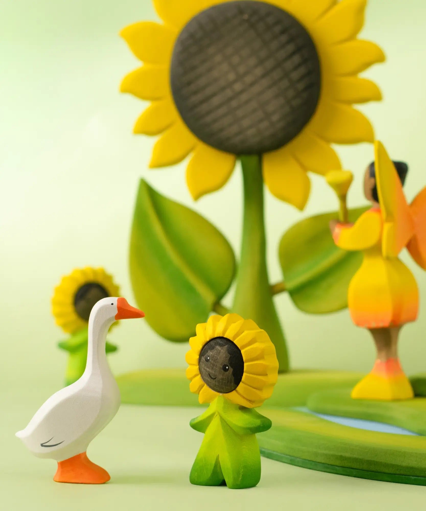 Bumbu handcrafted wooden festive goose decorative figure standing next to a wooden sunflowers child figure