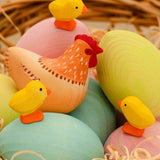 Bumbu handcrafted wooden hen figure resting on blue, green and pink eggs and yellow chick figures