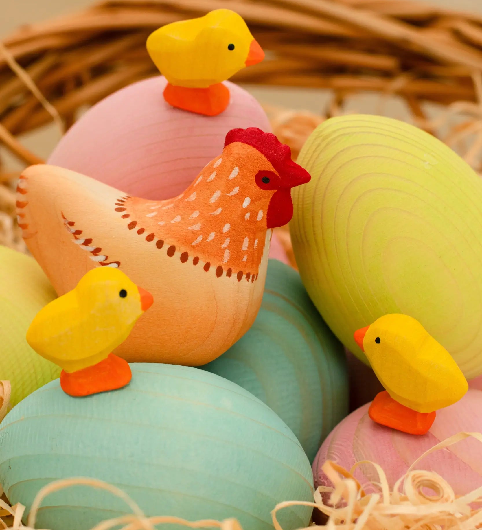 Bumbu handcrafted wooden hen figure resting on blue, green and pink eggs and yellow chick figures