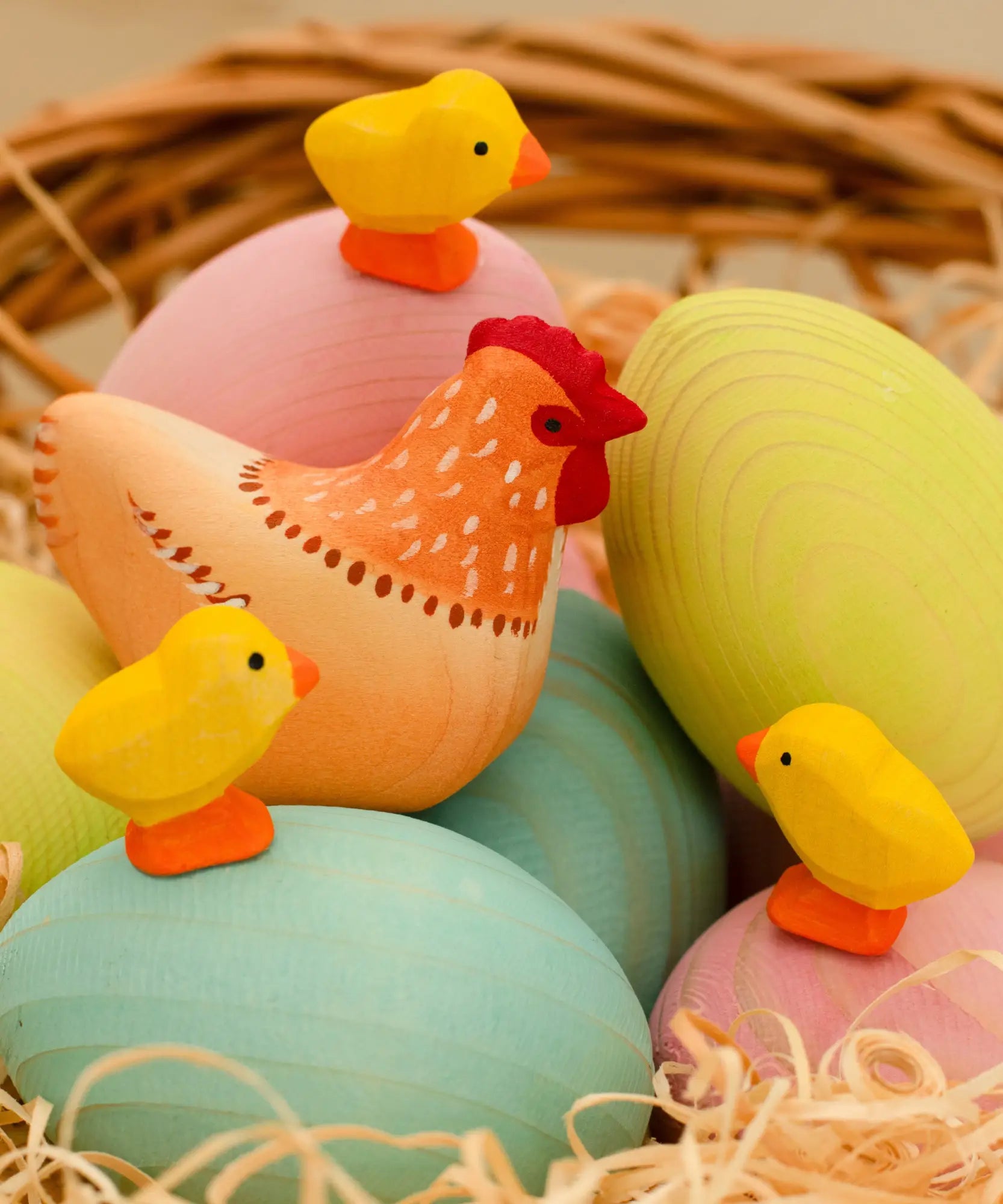 Bumbu handcrafted wooden hen figure resting on blue, green and pink eggs and yellow chick figures