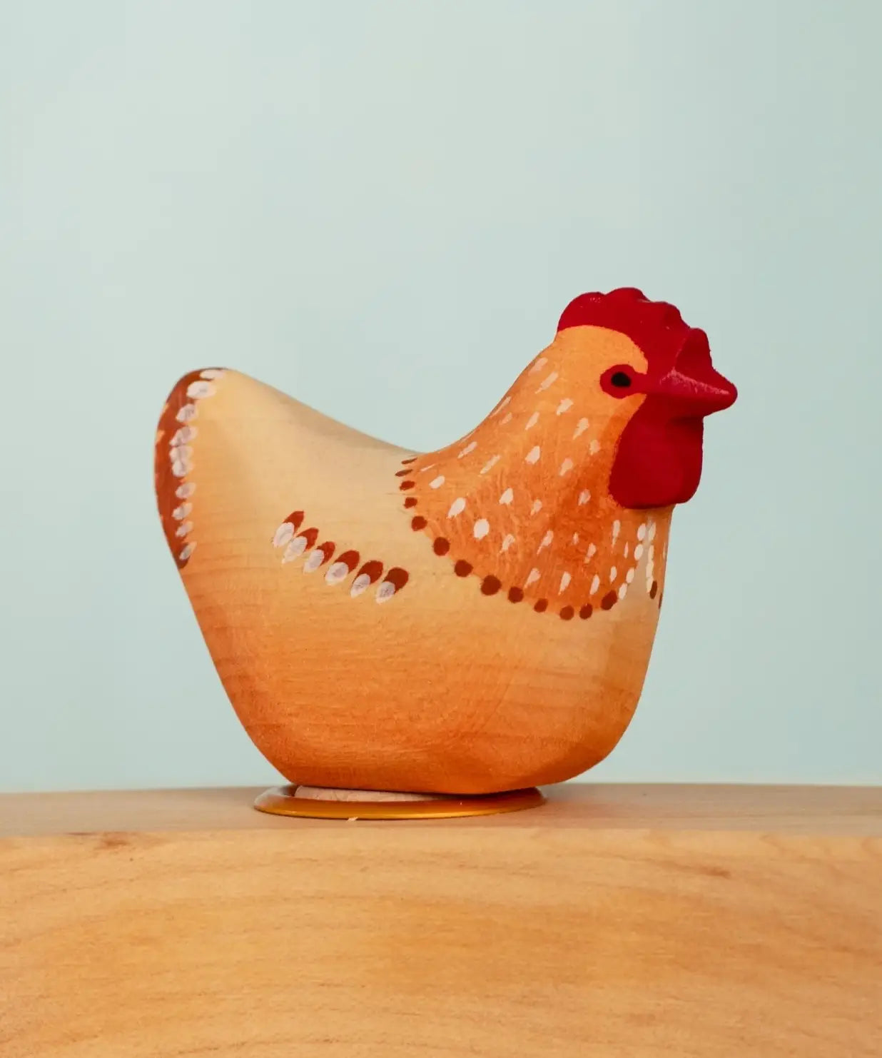 Bumbu wooden hand painted brown festive hen decorative figure standing in a celebration ring against a blue background