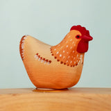 Bumbu wooden hand painted brown festive hen decorative figure standing in a celebration ring against a blue background