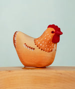 Bumbu wooden hand painted brown festive hen decorative figure standing in a celebration ring against a blue background