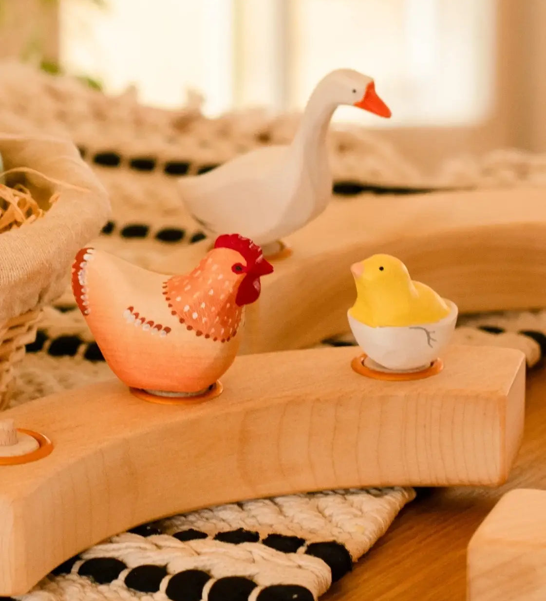 Hen, goose and chick in a egg Bumbu wooden decorative figures standing in a wooden celebration ring on a table