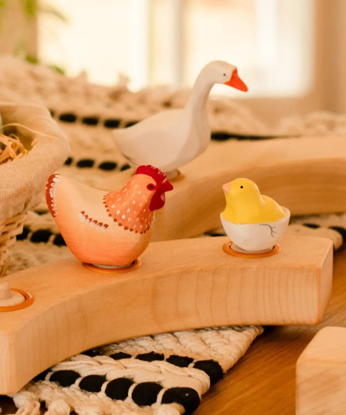 Hen, goose and chick in a egg Bumbu wooden decorative figures standing in a wooden celebration ring on a table