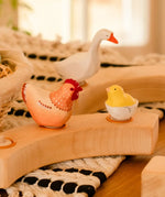Hen, goose and chick in a egg Bumbu wooden decorative figures standing in a wooden celebration ring on a table