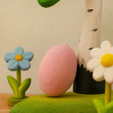 Bumbu handcrafted wooden egg decorative figure in pink resting on a tree with spring flowers