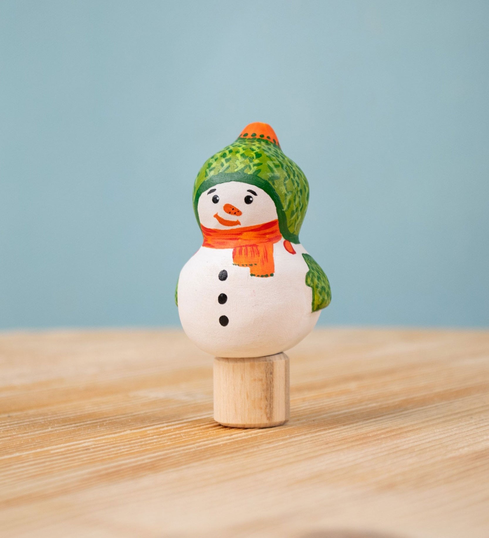 Bumbu Festive Snowman Celebration decorative Figure to fit on a Grimm's celebration ring. The handpainted snowman figure has a green hat with matching gloves and an orange scarf. These festive figures are perfect for your Christmas celebration ring set up. These expertly hand crafted items are part of a large range of wooden toys available here at Babipur.  