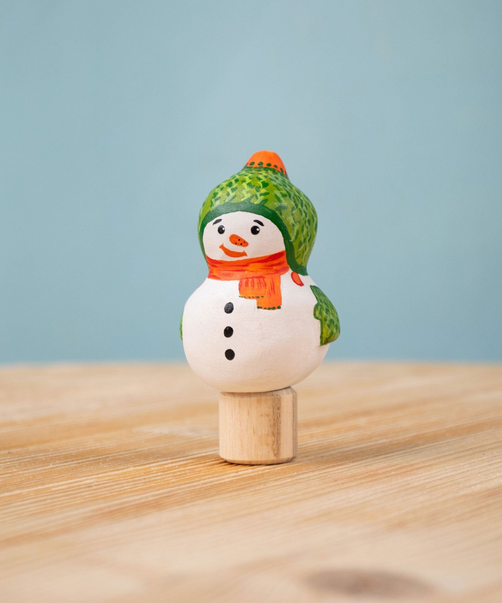 Bumbu Festive Snowman Celebration decorative Figure to fit on a Grimm's celebration ring. The handpainted snowman figure has a green hat with matching gloves and an orange scarf. These festive figures are perfect for your Christmas celebration ring set up. These expertly hand crafted items are part of a large range of wooden toys available here at Babipur.  