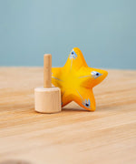 Bumbu yellow Festive Star Celebration decorative Figure to fit on a Grimm's celebration ring. The wooden yellow star is shown separated from the wooden base that comes with it.  These festive figures are perfect for your Christmas celebration ring set up. These expertly hand crafted items are part of a large range of wooden toys available here at Babipur. 