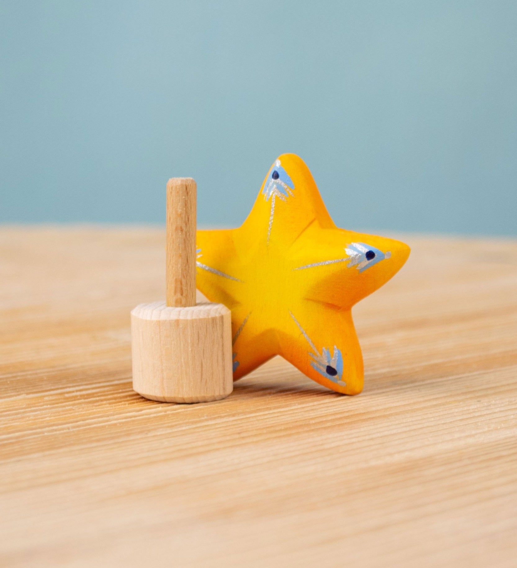 Bumbu yellow Festive Star Celebration decorative Figure to fit on a Grimm's celebration ring. The wooden yellow star is shown separated from the wooden base that comes with it.  These festive figures are perfect for your Christmas celebration ring set up. These expertly hand crafted items are part of a large range of wooden toys available here at Babipur. 