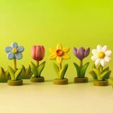Collection of Bumbu flower decorative flowers on green wooden bases with bushes in the background