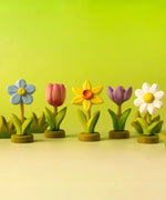 Collection of Bumbu flower decorative flowers on green wooden bases with bushes in the background