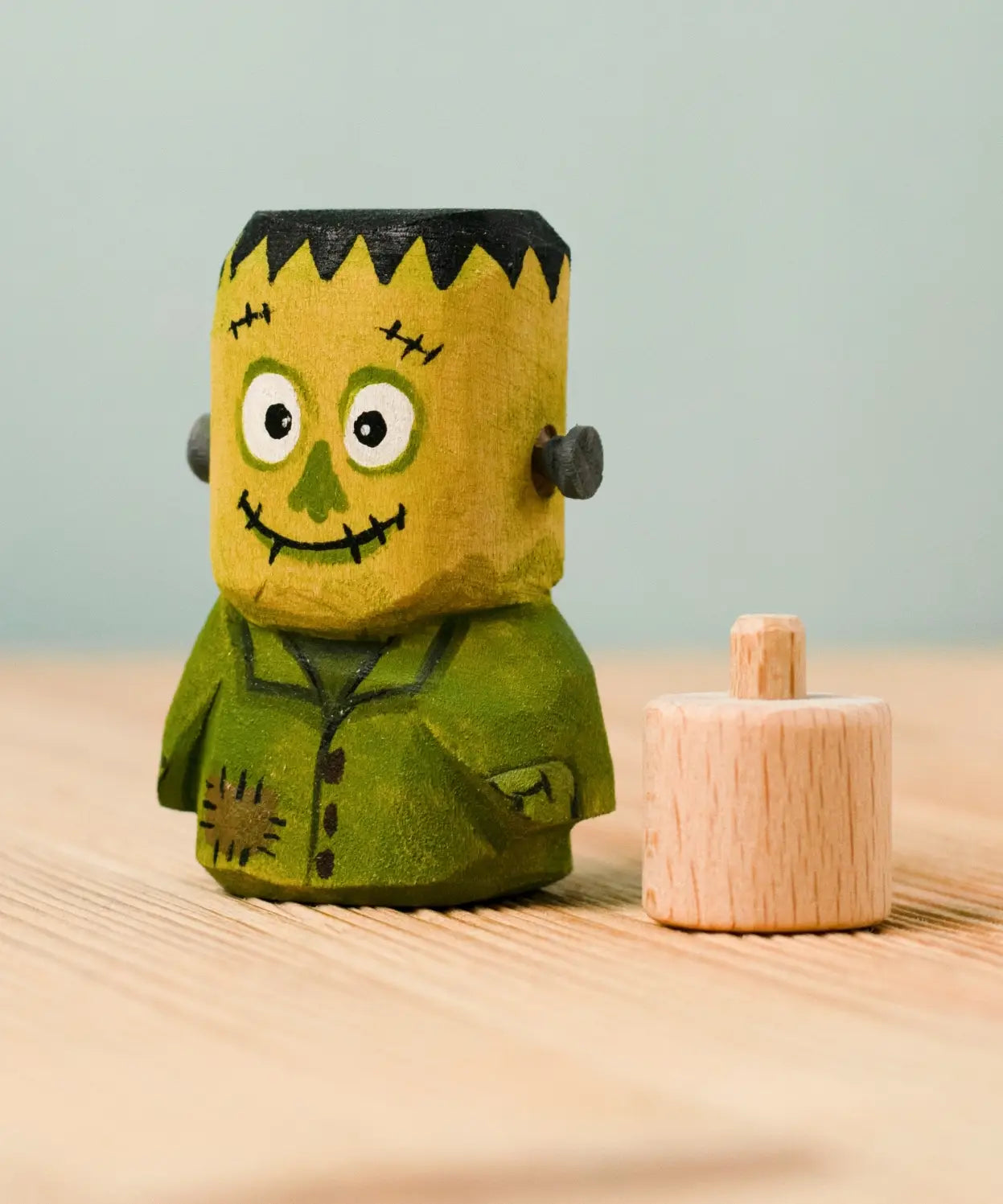 Bumbu handcrafted wooden Frankenstein halloween decorative figure next to a wooden display peg
