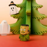 Bumbu handcrafted wooden Frankenstein halloween decorative figure in front of a tree and spooky ghost figures