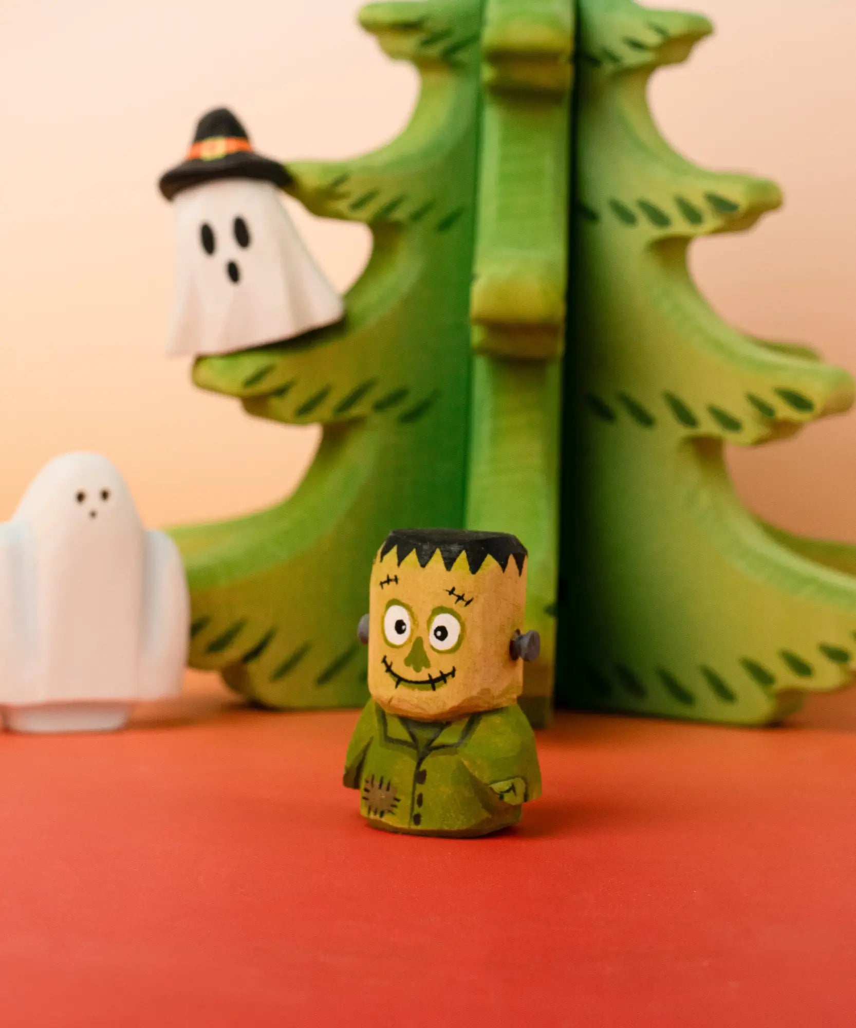 Bumbu handcrafted wooden Frankenstein halloween decorative figure in front of a tree and spooky ghost figures