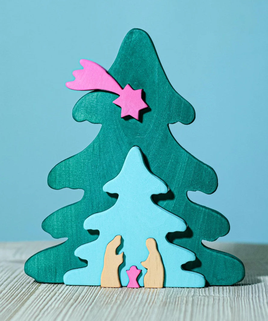 A Bumbu Christmas Tree Nativity Puzzle in a Fuchsia colour way placed on a wooden surface. 