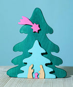 A Bumbu Christmas Tree Nativity Puzzle in a Fuchsia colour way placed on a wooden surface. 