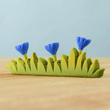 Bumbu large grass with 3 blue flowers wooden toy scenery piece placed on a wooden surface. 