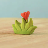 Bumbu small wooden grass with orange flower scenery piece placed on a wooden surface.