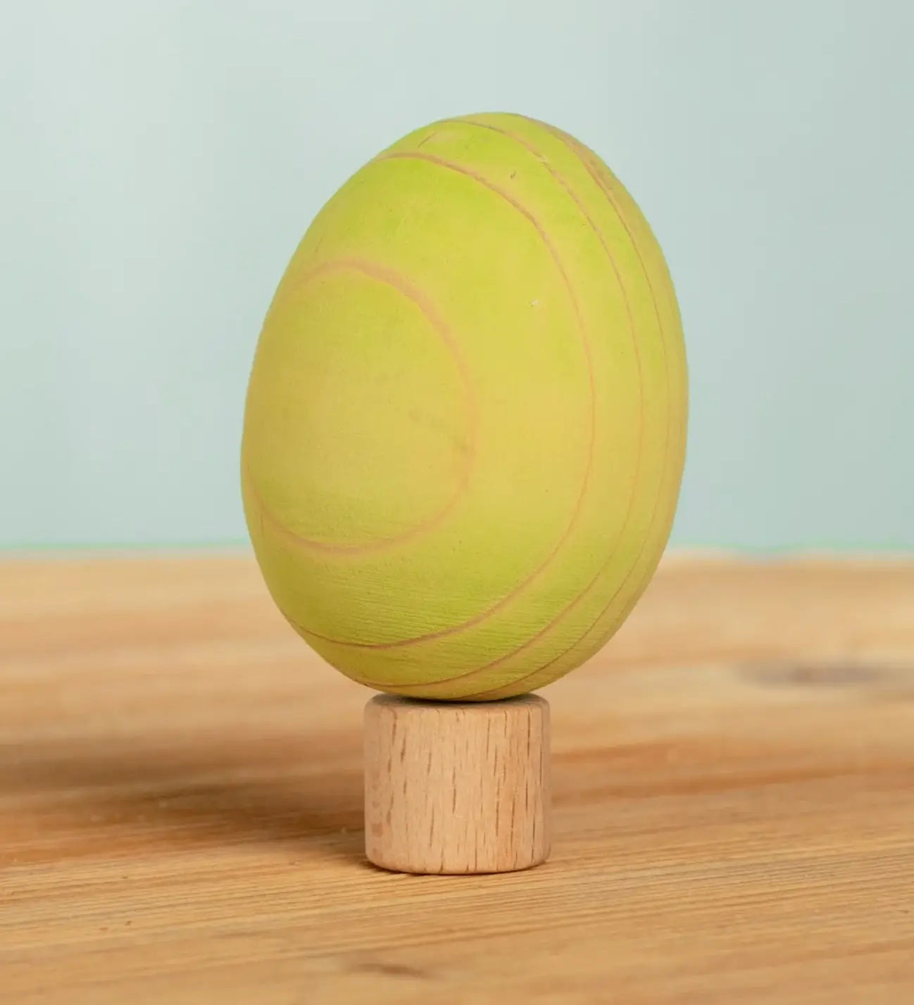 Bumbu handcrafted wooden green egg figure standing on wooden base for Grimms celebration ring