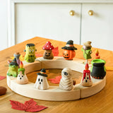 Twelve Bumbu Halloween themed celebration ring figures placed on a natural wooden celebration ring. 