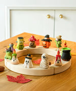 Twelve Bumbu Halloween themed celebration ring figures placed on a natural wooden celebration ring. 