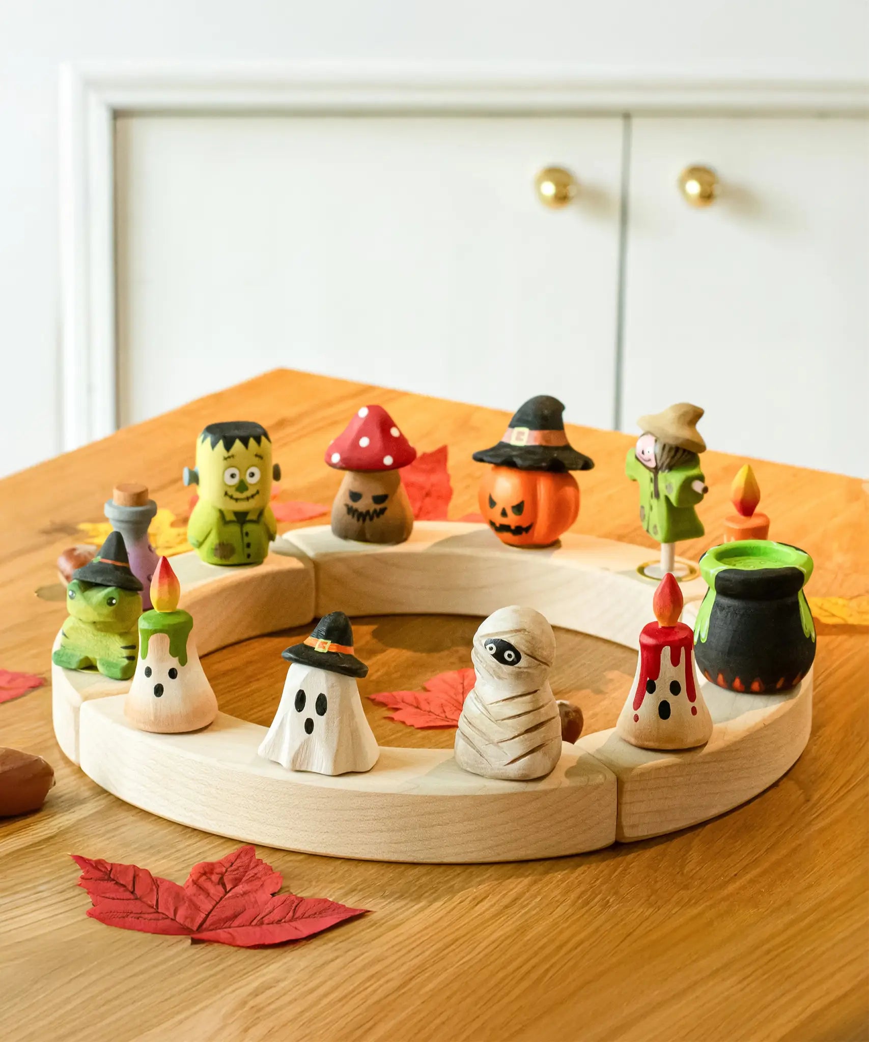 Twelve Bumbu Halloween themed celebration ring figures placed on a natural wooden celebration ring. 