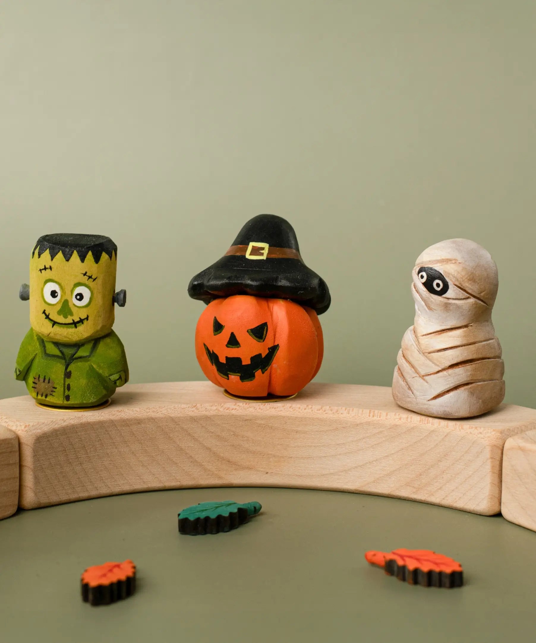 Bumbu handcrafted wooden Frankenstein halloween figure standing on a celebration ring piece next to a pumpkin and mummy decorative figure