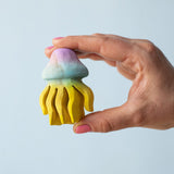 A hand holding the Bumbu handmade and painted wooden jellyfish toy. 
