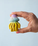 A hand holding the Bumbu handmade and painted wooden jellyfish toy. 