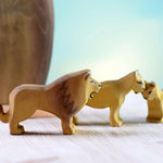 female and baby lion toys stood on a white wooden background