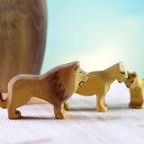 female and baby lion toys stood on a white wooden background