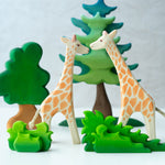 2 Ostheimer giraffe figures stood on a white background behind the Bumbu small and large wooden shrub toys