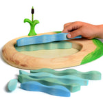 Close up of hand building the plastic free Bumbu slotting wooden lake puzzle on a white background