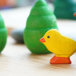 Bumbu small wooden chick figure on a wooden table in front of a Grapat mandala tree