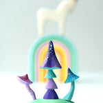 Close up of the Bumbu plastic-free enchanted mushroom toys on a white background in front of a stacking rainbow and unicorn figure