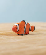 The Bumbu hand carved wooden Clownfish toy. It is hand painted in orange with black and white stripes.