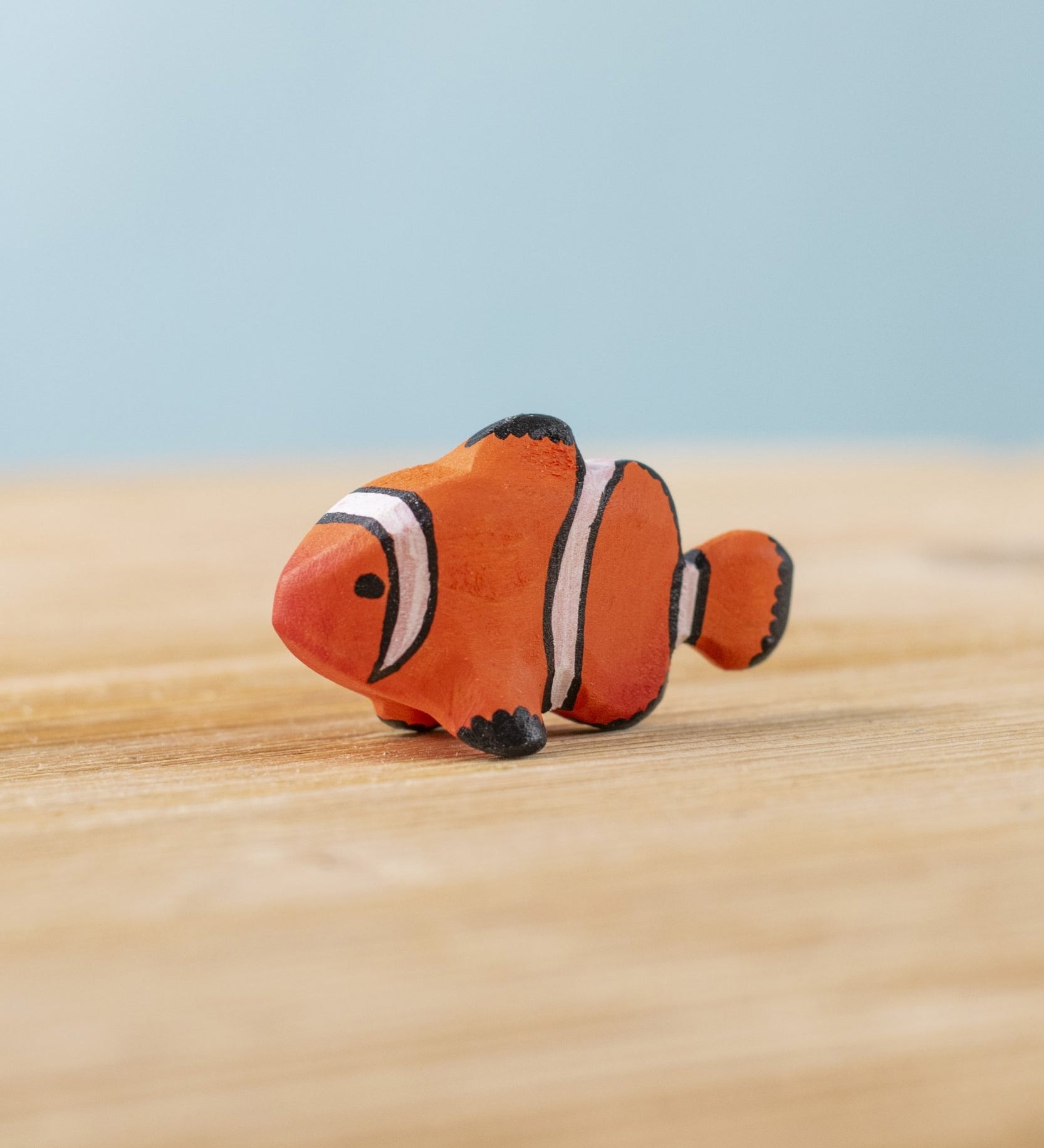 The Bumbu hand carved wooden Clownfish toy. It is hand painted in orange with black and white stripes.