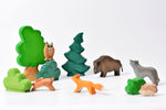 Bumbu large tree and other handmade wooden Bumbu toys scattered on a white background to make an animal nature scene