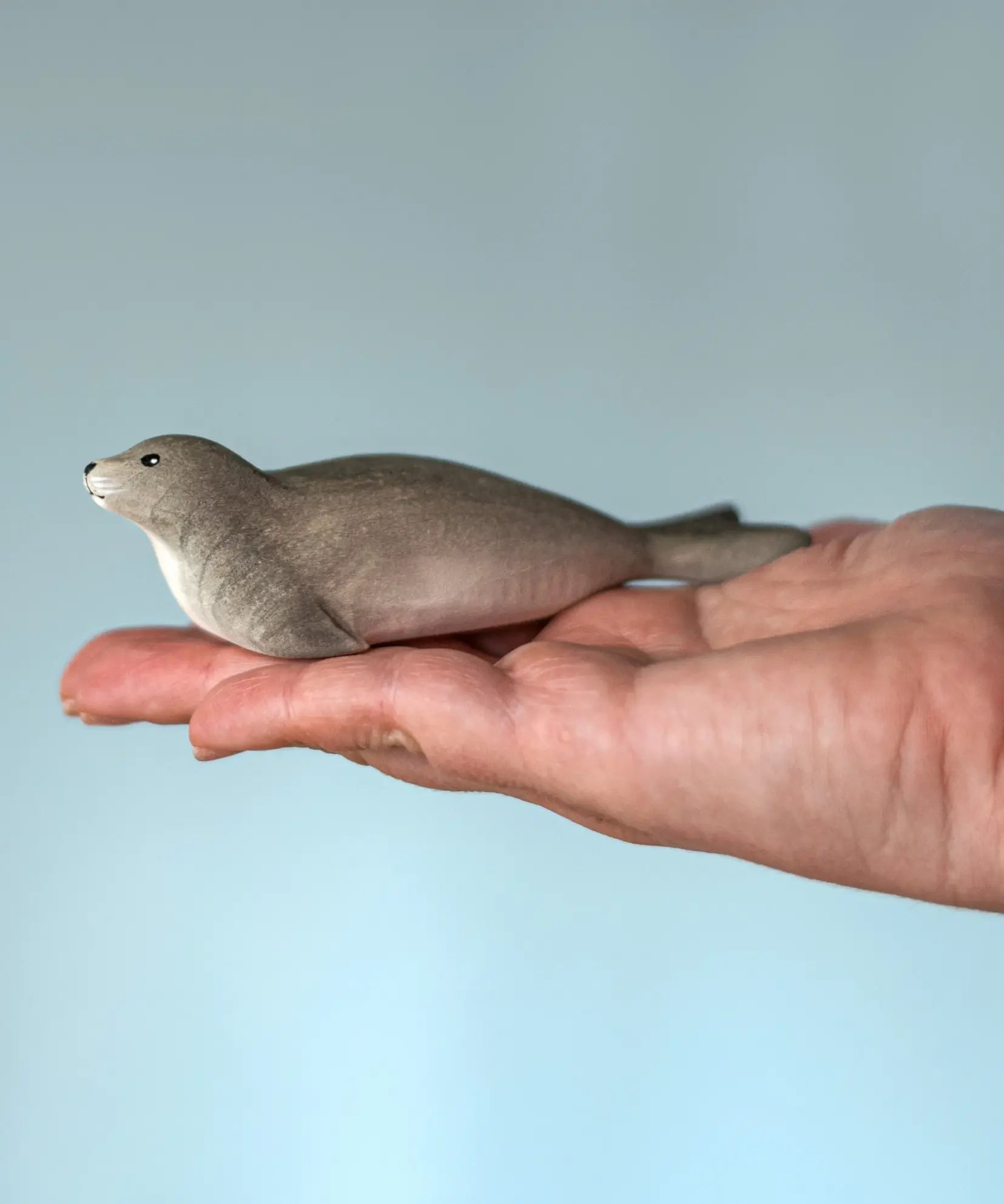 Bumbu harp seal handmade wooden toy figure in an adult's hand