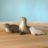 Two Bumbu Toys harp seal and a pup handmade wooden toy figures placed on a wooden surface.